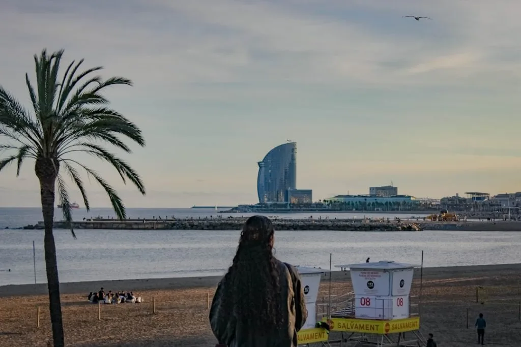 Woman on beach with modern building by the sea