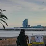 Woman on beach with modern building by the sea