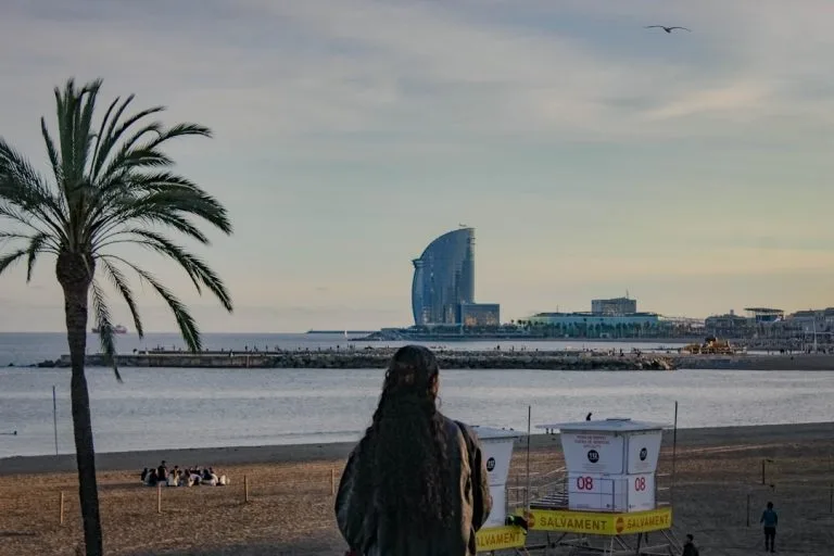 Woman on beach with modern building by the sea