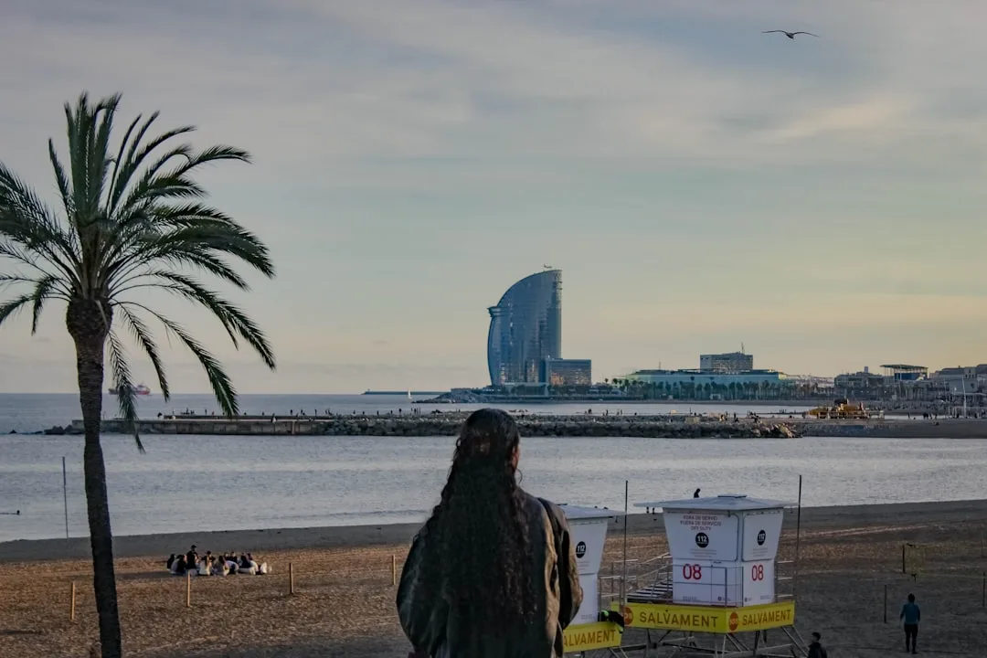 Woman on beach with modern building by the sea