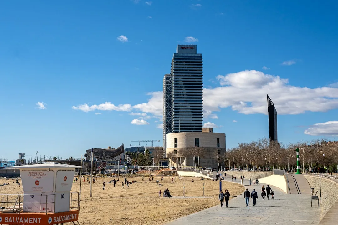 A group of people walking along a beach next to a tall building