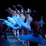a group of ballerinas standing on a stage with their arms in the air