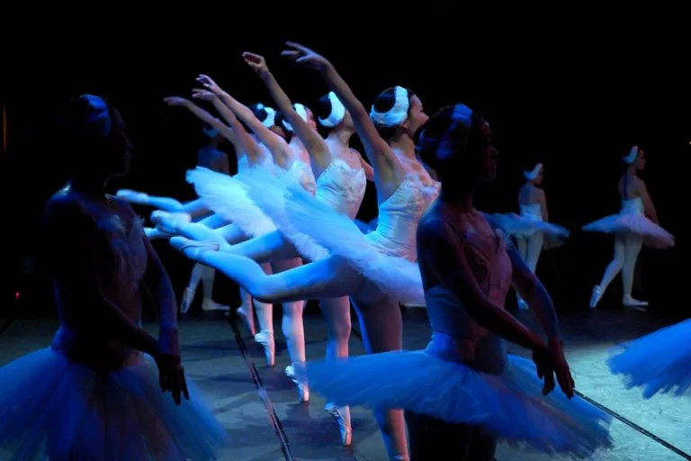 a group of ballerinas standing on a stage with their arms in the air