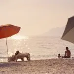 A group of people sitting on top of a sandy beach