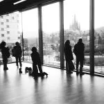 Silhouettes of people looking out large windows at city skyline