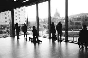 Silhouettes of people looking out large windows at city skyline