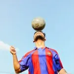 A man is balancing a soccer ball on his head