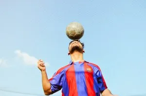 A man is balancing a soccer ball on his head