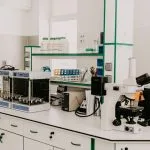 A laboratory workbench with a microscope and analytical equipment in a bright room