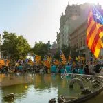 a crowd of people standing around a fountain with flags