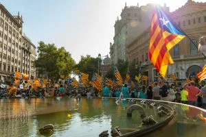 a crowd of people standing around a fountain with flags