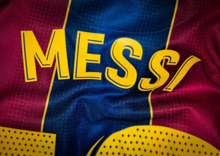 Yellow lettering reading MESS on a blue and red patterned sports jersey